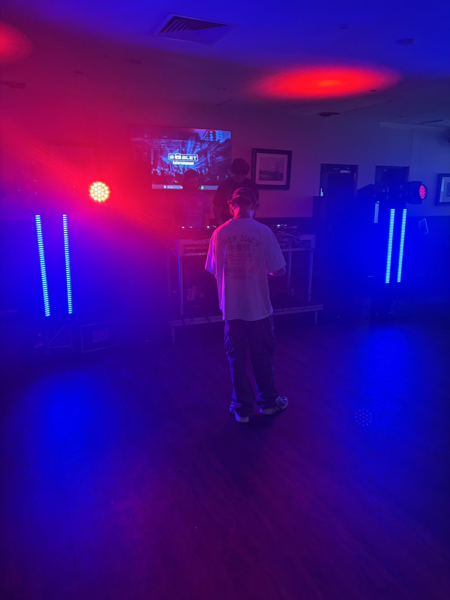 DJ booth lit with red and blue LED totems at a RiddimSEQ show