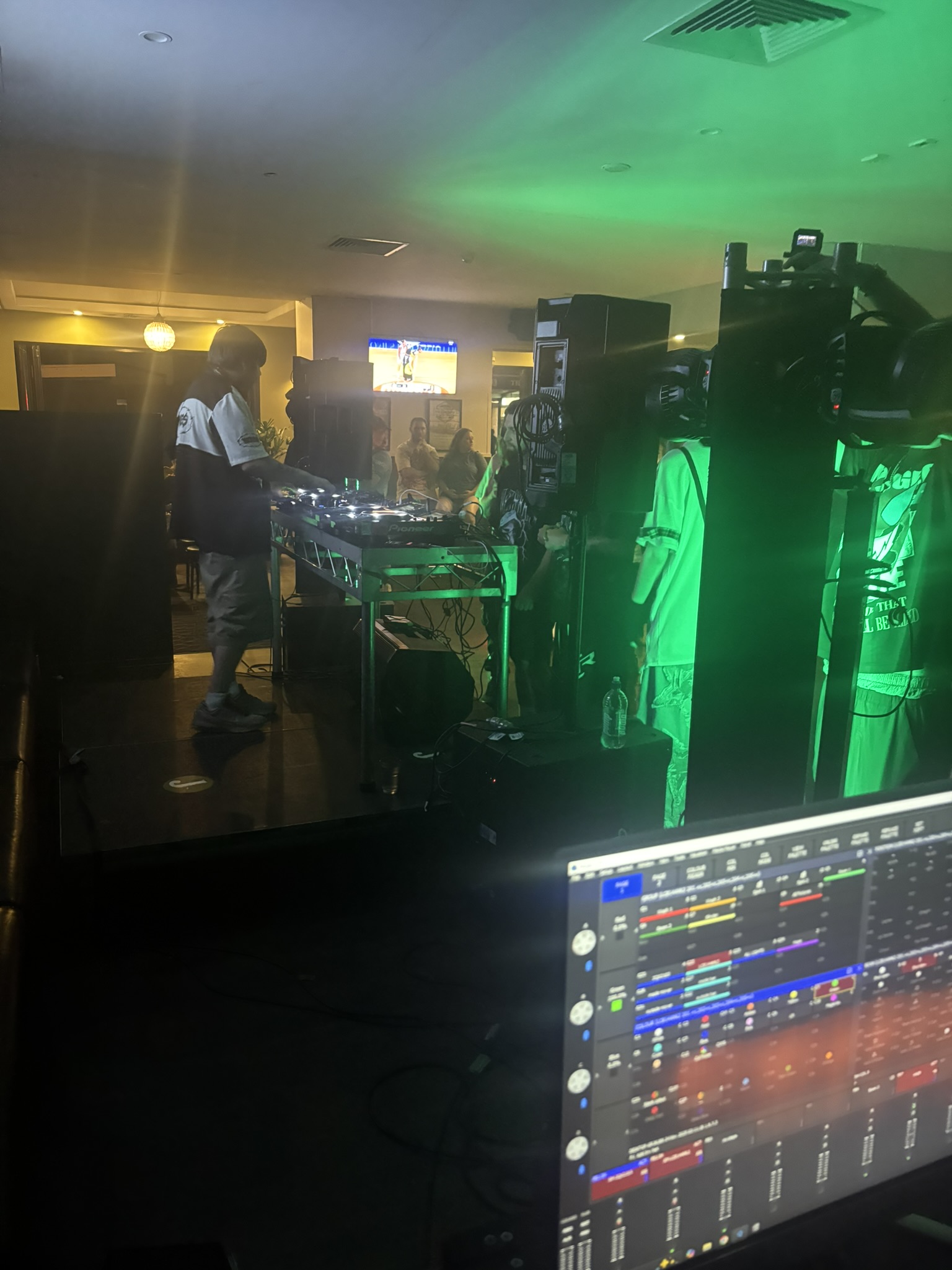 DJ performing under green wash with the lighting desk running the show in the foreground