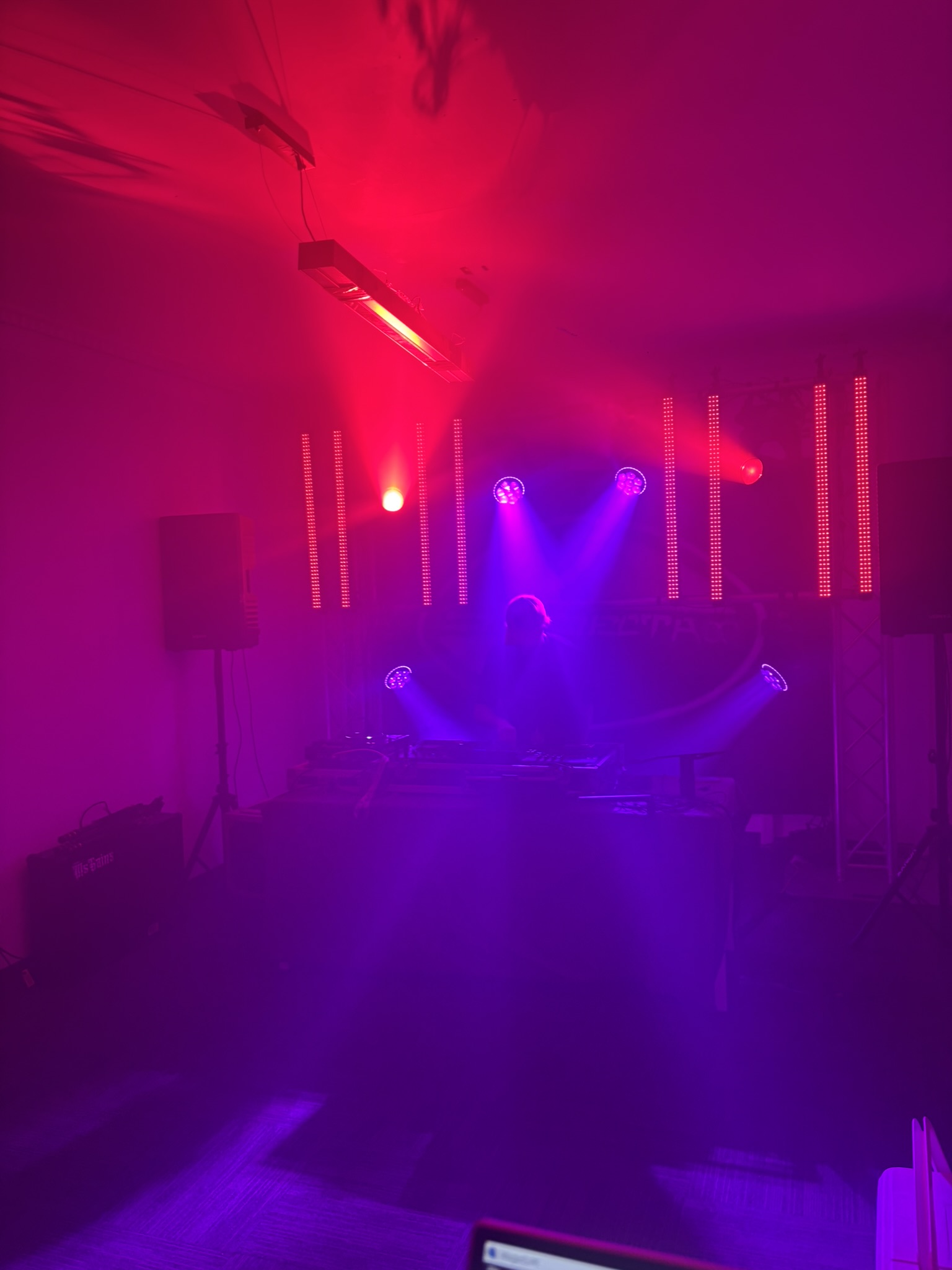 DJ silhouetted against red and purple moving-head beams in front of the SubSecta backdrop